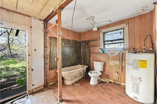 interior space with hardwood / wood-style floors, a bathtub, electric water heater, ceiling fan, and toilet