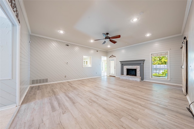 unfurnished living room with wooden walls, light hardwood / wood-style flooring, ceiling fan, and crown molding