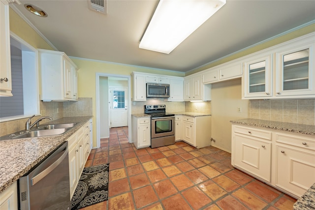 kitchen with decorative backsplash, ornamental molding, stainless steel appliances, sink, and white cabinetry