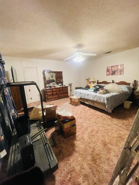 carpeted bedroom with ceiling fan and a textured ceiling