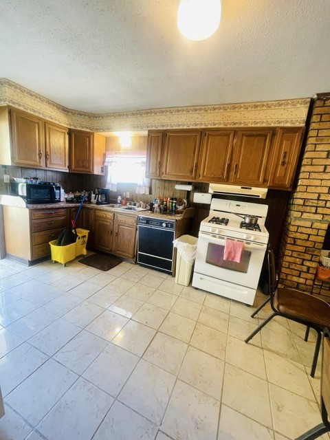 kitchen with sink, black appliances, and a textured ceiling