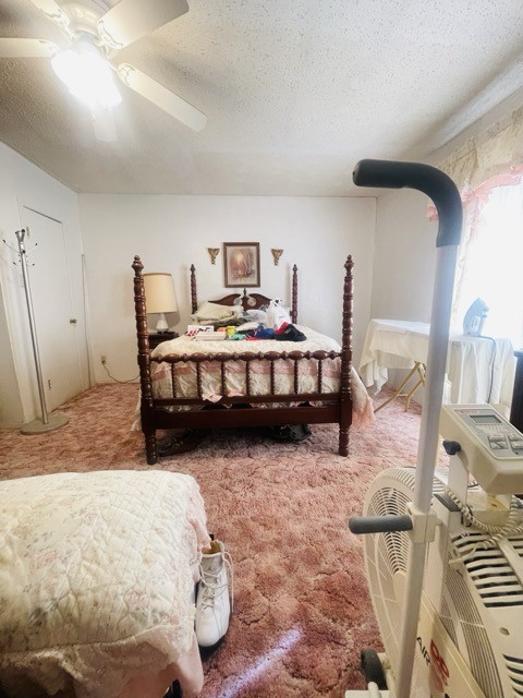 bedroom with ceiling fan, carpet flooring, and a textured ceiling