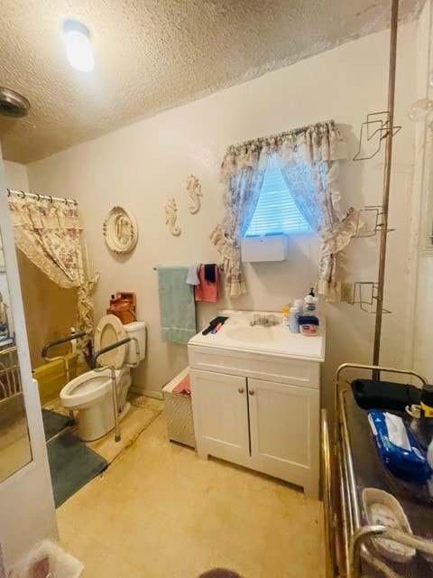 bathroom with vanity, toilet, and a textured ceiling