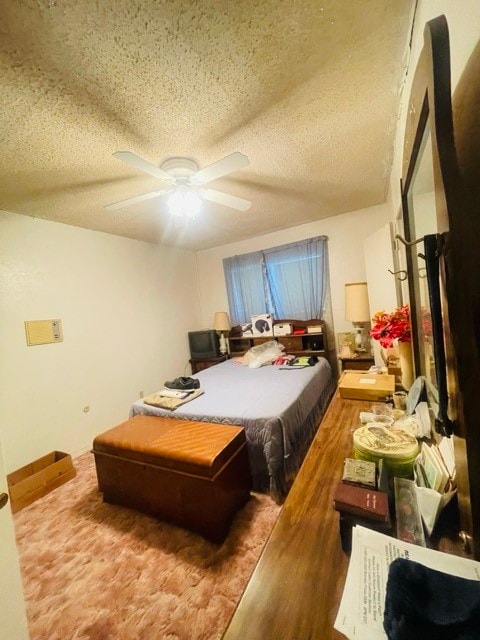 bedroom featuring ceiling fan, hardwood / wood-style floors, and a textured ceiling