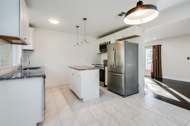 kitchen with pendant lighting, white cabinets, sink, a kitchen island, and stainless steel appliances