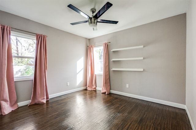 empty room featuring ceiling fan, dark wood-type flooring, and a wealth of natural light