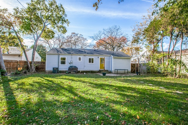 rear view of house with central AC unit and a lawn