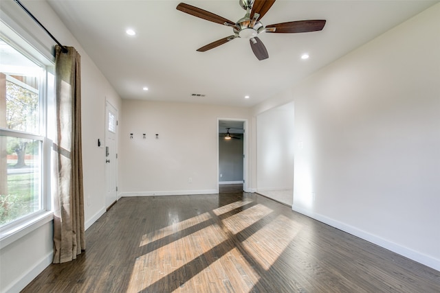 unfurnished room featuring plenty of natural light, ceiling fan, and dark hardwood / wood-style flooring