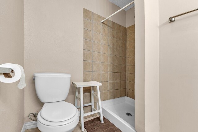 bathroom with tiled shower, hardwood / wood-style floors, and toilet