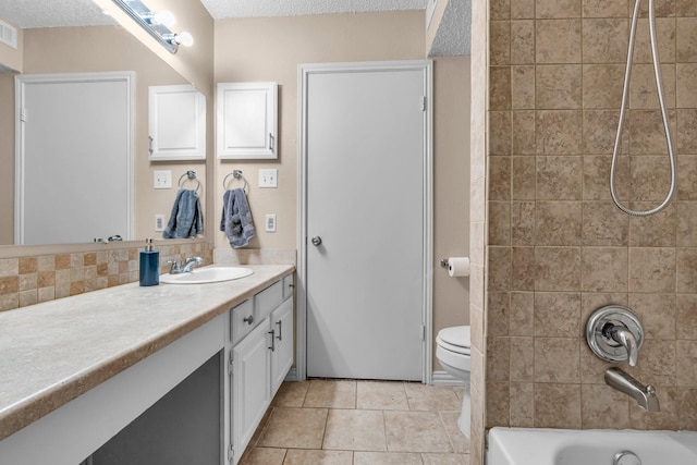 full bathroom featuring vanity, a textured ceiling, tile patterned floors, toilet, and tiled shower / bath