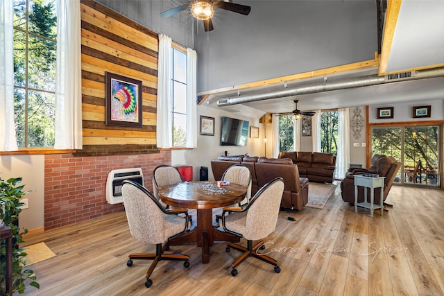 dining room featuring heating unit, wooden walls, light hardwood / wood-style flooring, and ceiling fan