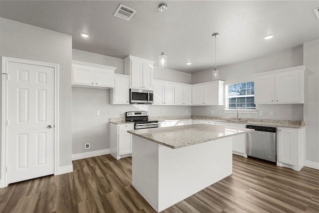 kitchen featuring white cabinets, appliances with stainless steel finishes, a center island, and dark hardwood / wood-style floors