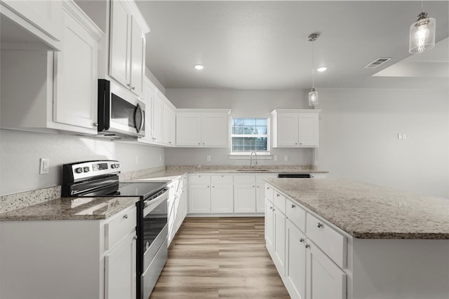 kitchen with appliances with stainless steel finishes, decorative light fixtures, white cabinetry, and sink