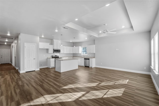 kitchen with a center island, dark wood-type flooring, white cabinets, ceiling fan, and appliances with stainless steel finishes