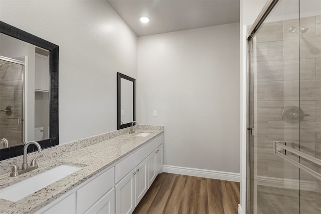 bathroom featuring hardwood / wood-style floors, vanity, a shower with shower door, and toilet