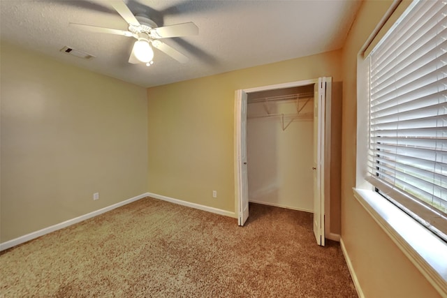 unfurnished bedroom with ceiling fan, carpet floors, a textured ceiling, and a closet