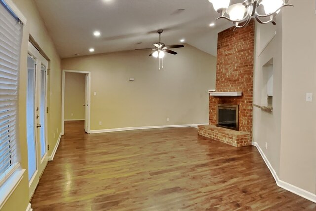 unfurnished living room with hardwood / wood-style floors, ceiling fan with notable chandelier, a fireplace, and vaulted ceiling