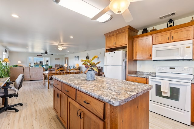 kitchen with light stone countertops, light hardwood / wood-style floors, a kitchen island, and white appliances