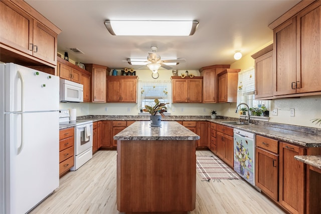 kitchen with light hardwood / wood-style floors, a center island, white appliances, and sink