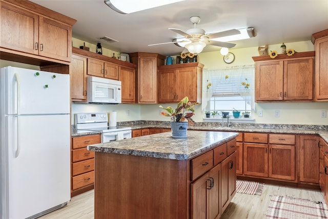 kitchen featuring light wood-type flooring, white appliances, ceiling fan, stone counters, and a kitchen island