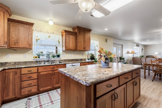 kitchen with sink, a kitchen island, a healthy amount of sunlight, and light wood-type flooring