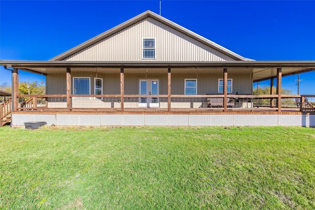 rear view of property with french doors, a wooden deck, and a lawn