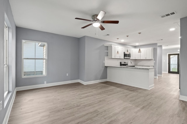 unfurnished living room with sink, a healthy amount of sunlight, and light hardwood / wood-style floors