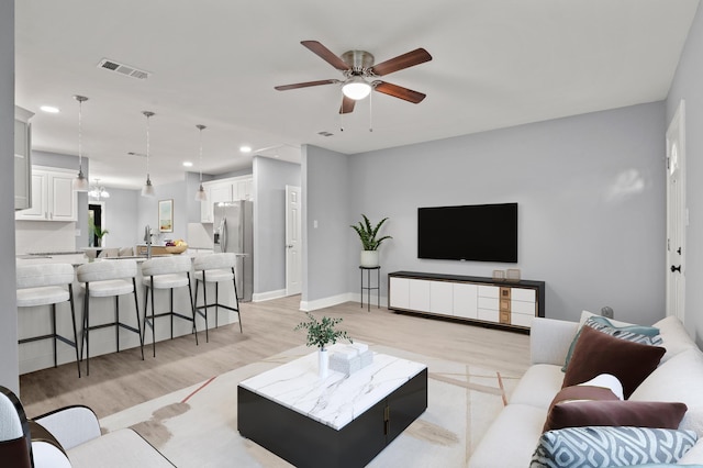 living room with ceiling fan and light hardwood / wood-style floors