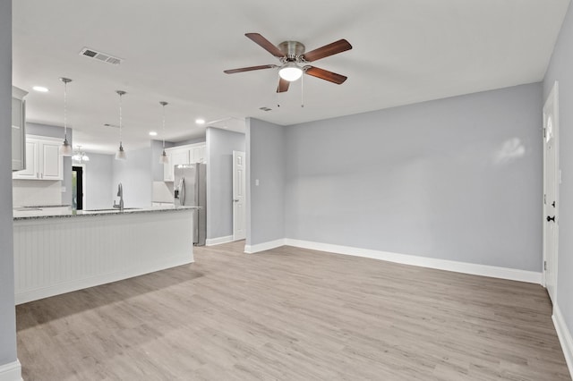 unfurnished living room featuring ceiling fan, sink, and light hardwood / wood-style floors