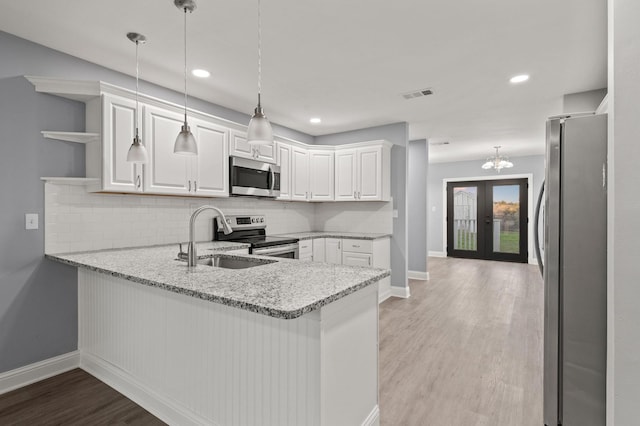 kitchen with kitchen peninsula, white cabinetry, pendant lighting, and appliances with stainless steel finishes