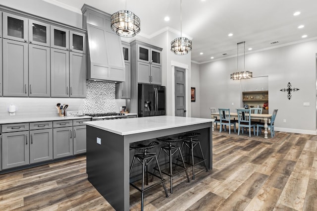 kitchen featuring a center island, refrigerator with ice dispenser, hanging light fixtures, and gray cabinetry