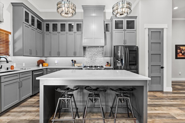 kitchen featuring crown molding, stainless steel appliances, decorative light fixtures, and a kitchen island