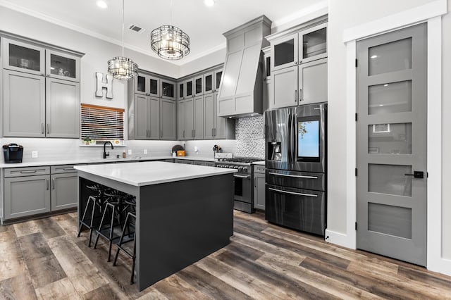 kitchen with ornamental molding, appliances with stainless steel finishes, a center island, and hanging light fixtures