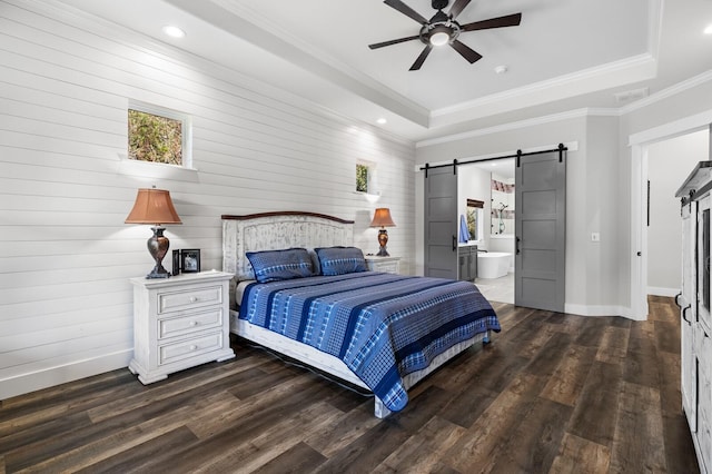 bedroom with a barn door, dark wood-type flooring, and a tray ceiling