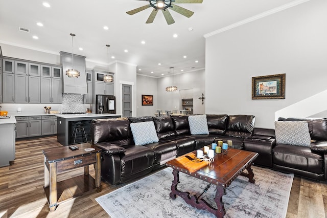 living room featuring ornamental molding, sink, ceiling fan with notable chandelier, and dark hardwood / wood-style flooring