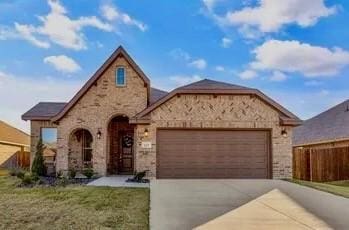 view of front of house with driveway, an attached garage, fence, and a front yard