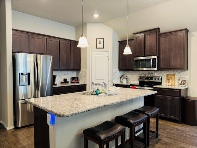 kitchen with stainless steel appliances, hanging light fixtures, and a kitchen island with sink