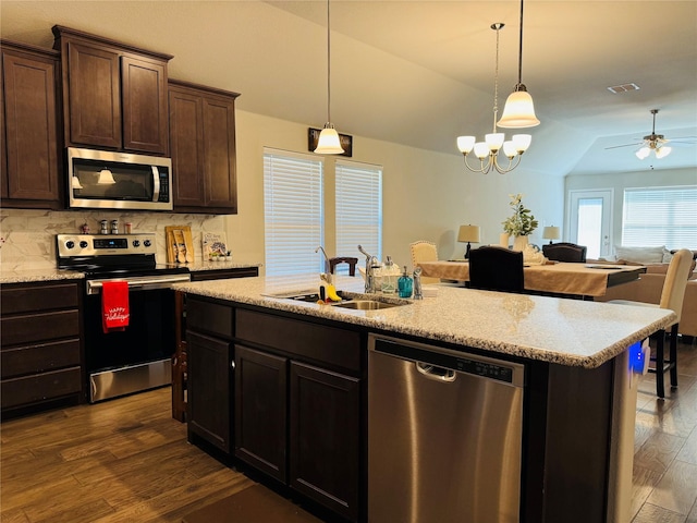 kitchen with stainless steel appliances, dark brown cabinets, a sink, and decorative light fixtures