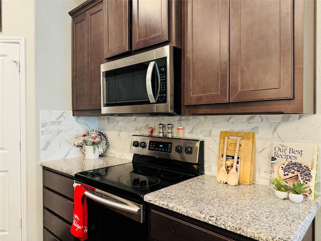 kitchen featuring stainless steel appliances, light stone counters, dark brown cabinetry, and tasteful backsplash