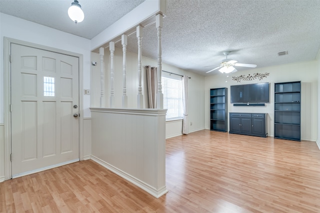 foyer entrance with ceiling fan, a textured ceiling, and light wood-type flooring