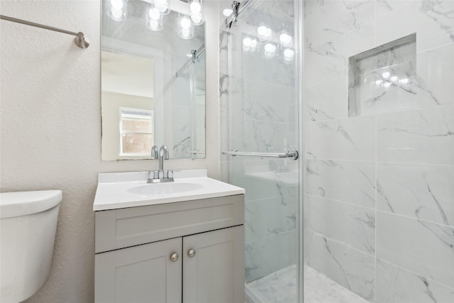 bathroom featuring a shower with shower door, vanity, and toilet