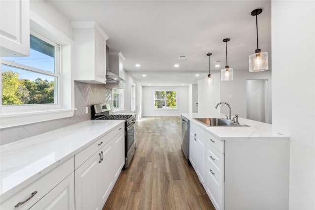 kitchen featuring decorative light fixtures, white cabinetry, stainless steel appliances, sink, and backsplash