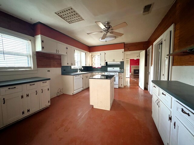 kitchen with white appliances, white cabinets, ceiling fan, a kitchen island, and concrete flooring