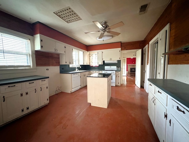 kitchen with white appliances, ceiling fan, concrete flooring, white cabinets, and a kitchen island