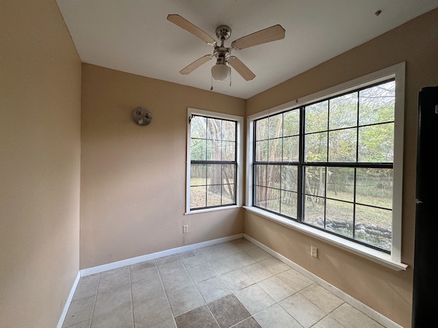 tiled spare room featuring plenty of natural light and ceiling fan