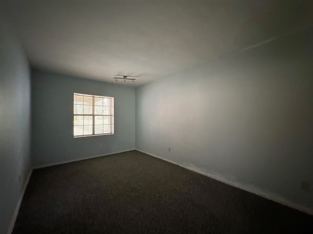 spare room with dark carpet