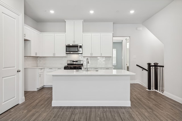 kitchen featuring dark wood-type flooring, sink, a center island with sink, appliances with stainless steel finishes, and white cabinets