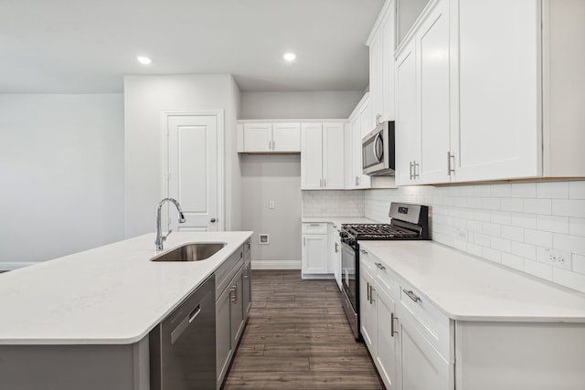 kitchen featuring white cabinets, a center island with sink, sink, appliances with stainless steel finishes, and dark hardwood / wood-style flooring