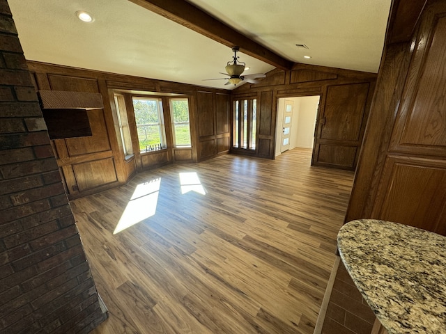 unfurnished living room with lofted ceiling with beams, ceiling fan, dark wood-type flooring, and wood walls