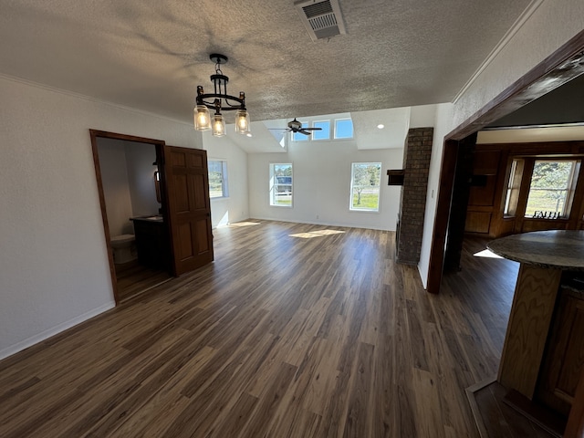 unfurnished living room featuring ceiling fan, dark wood-type flooring, a healthy amount of sunlight, and a textured ceiling